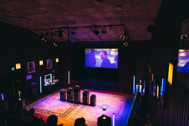 Guests seated at the Nuance Audio launch event, with the film playing on a large screen